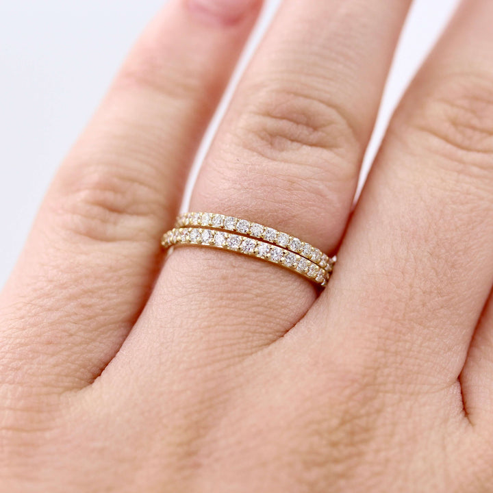 a model wearing two gold pavé wedding bands