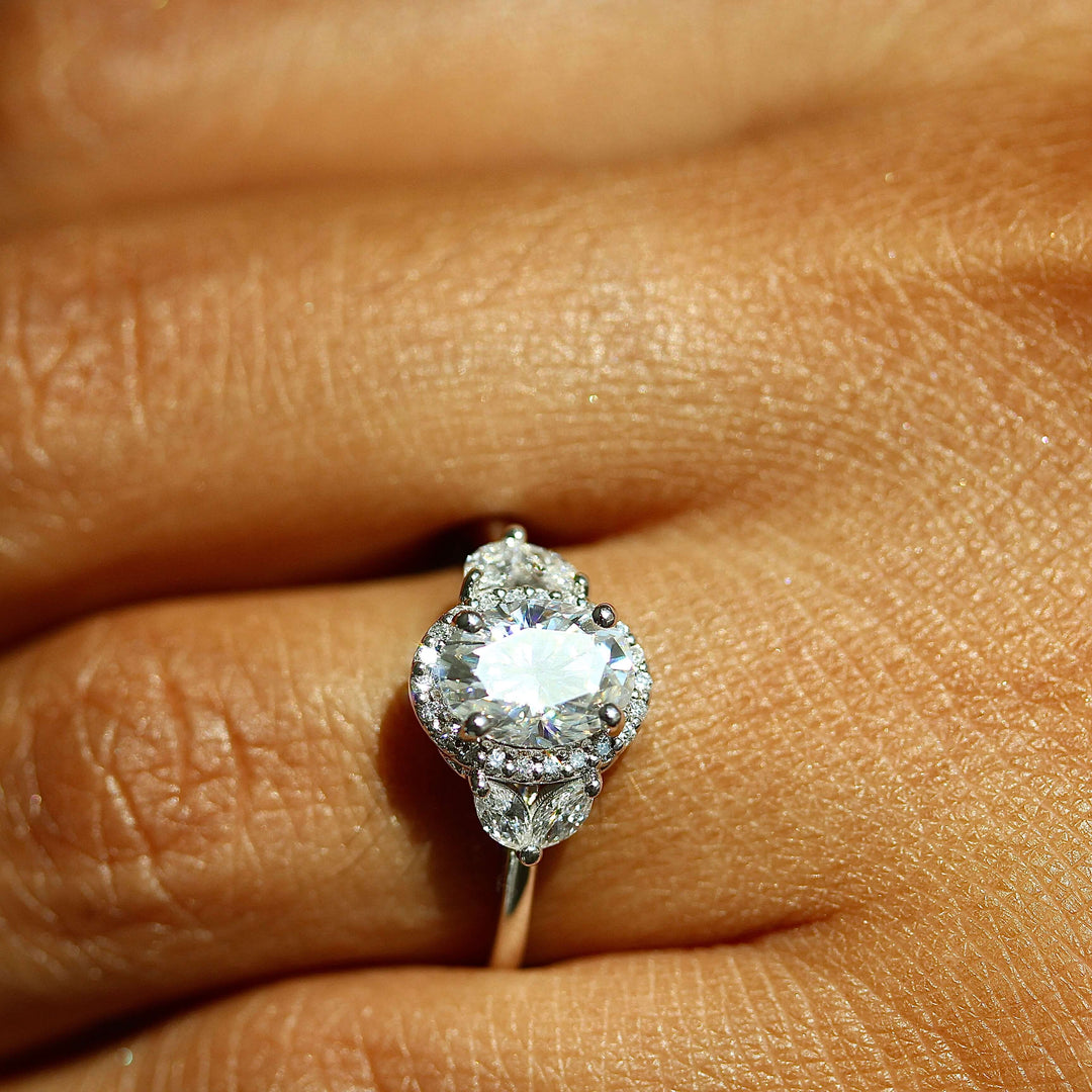 an oval diamond engagement ring worn on a hand.