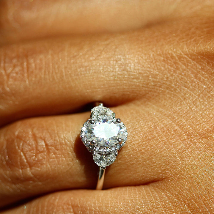 an oval diamond engagement ring worn on a hand.