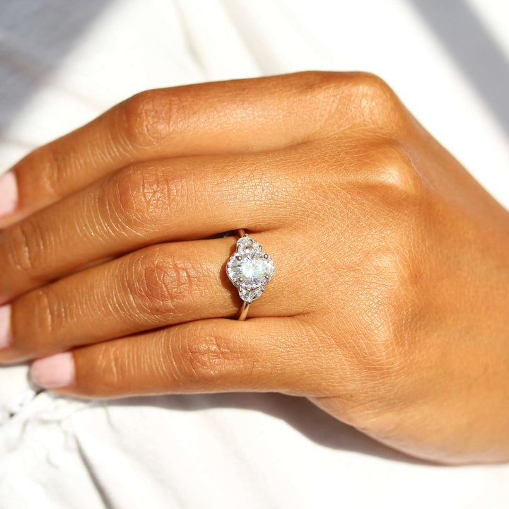 an oval halo engagement ring on a woman’s hand.
