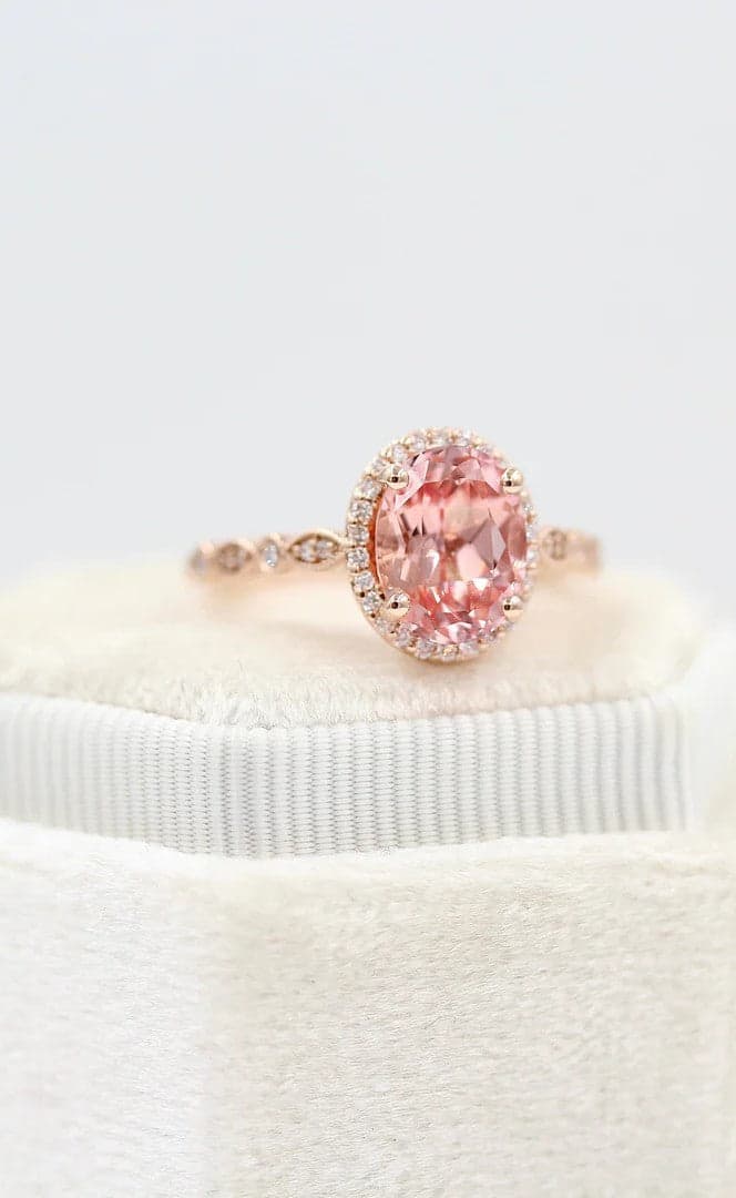 hand wearing peachy pink created sapphire ring