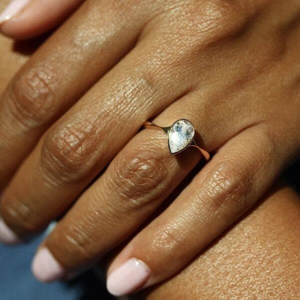 hand wearing pear bezel solitaire engagement ring