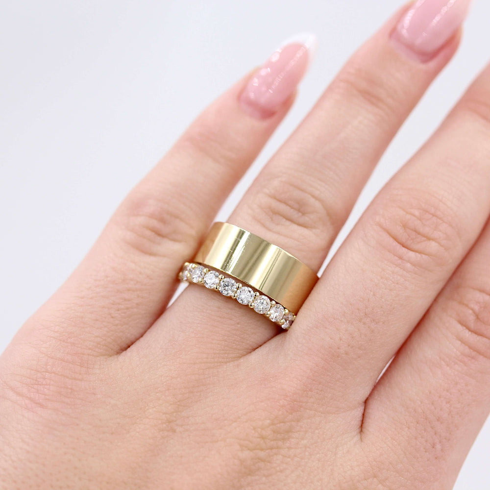 a thick gold band and thin diamond ring stacked on a woman’s finger