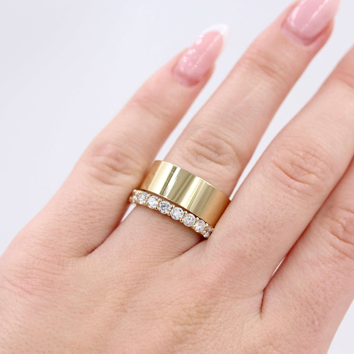 a thick gold band and thin diamond ring stacked on a woman’s finger