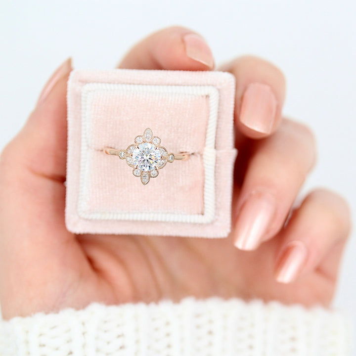 The Harlow Ring (Round) in rose gold in a pink velvet ring box held by a hand