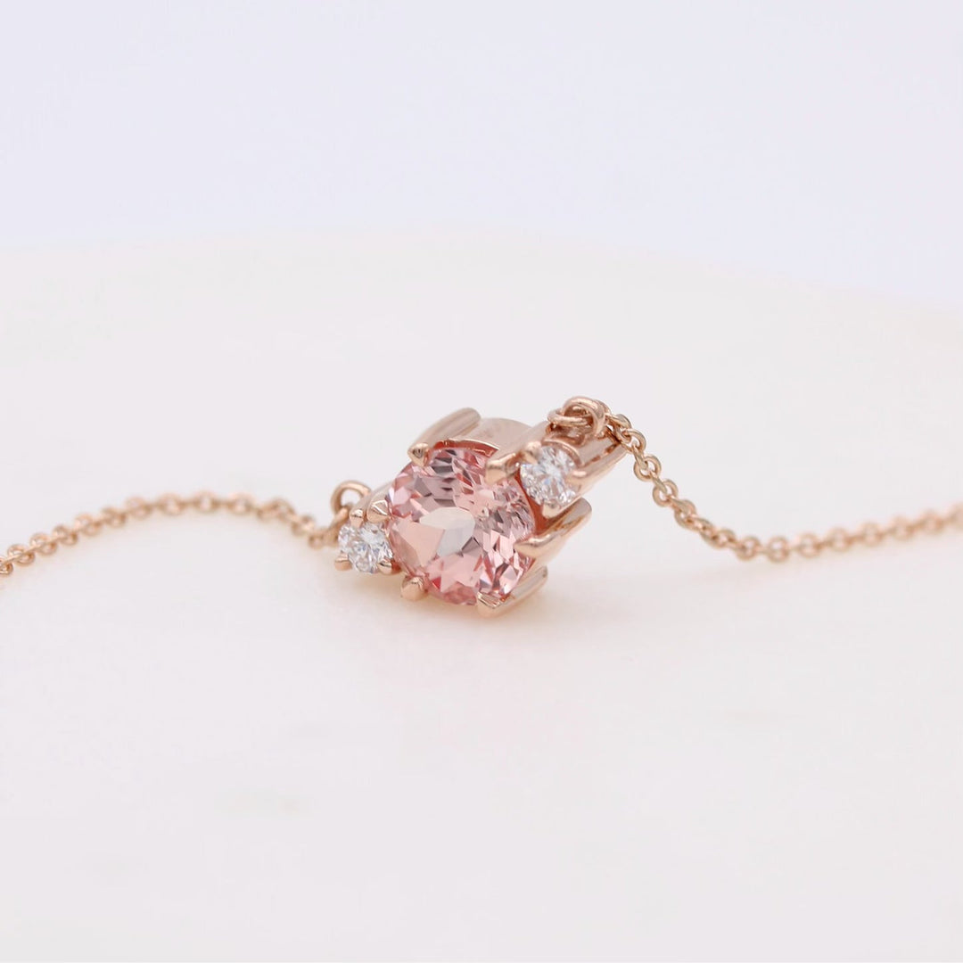 rose gold necklace with peachy-pink sapphire center and round diamond accents on a rose gold chain