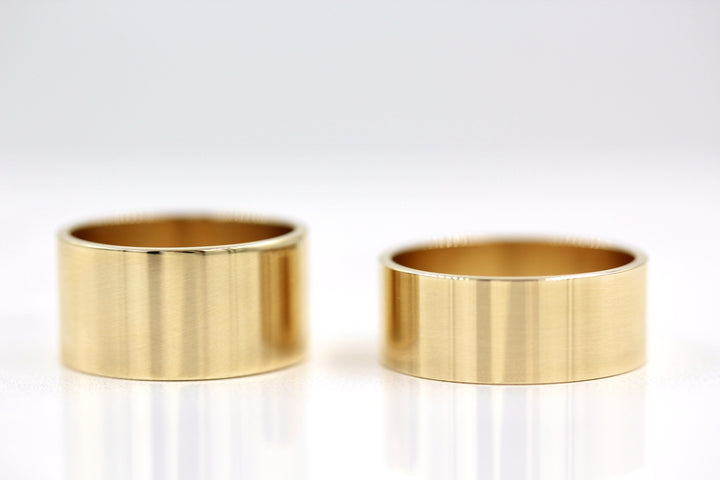 Two cigar wedding bands on a white reflective table
