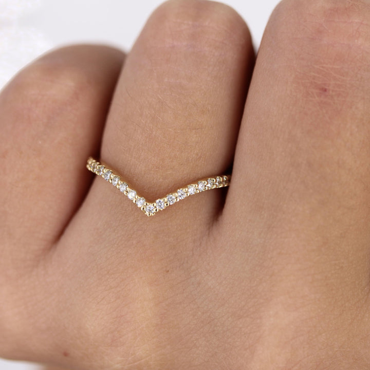 Hand wearing v-shaped lab-grown diamond wedding band in yellow gold