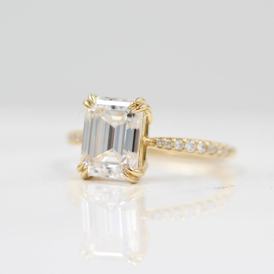 Slightly angled emerald cut engagement ring with tapered pavé band
