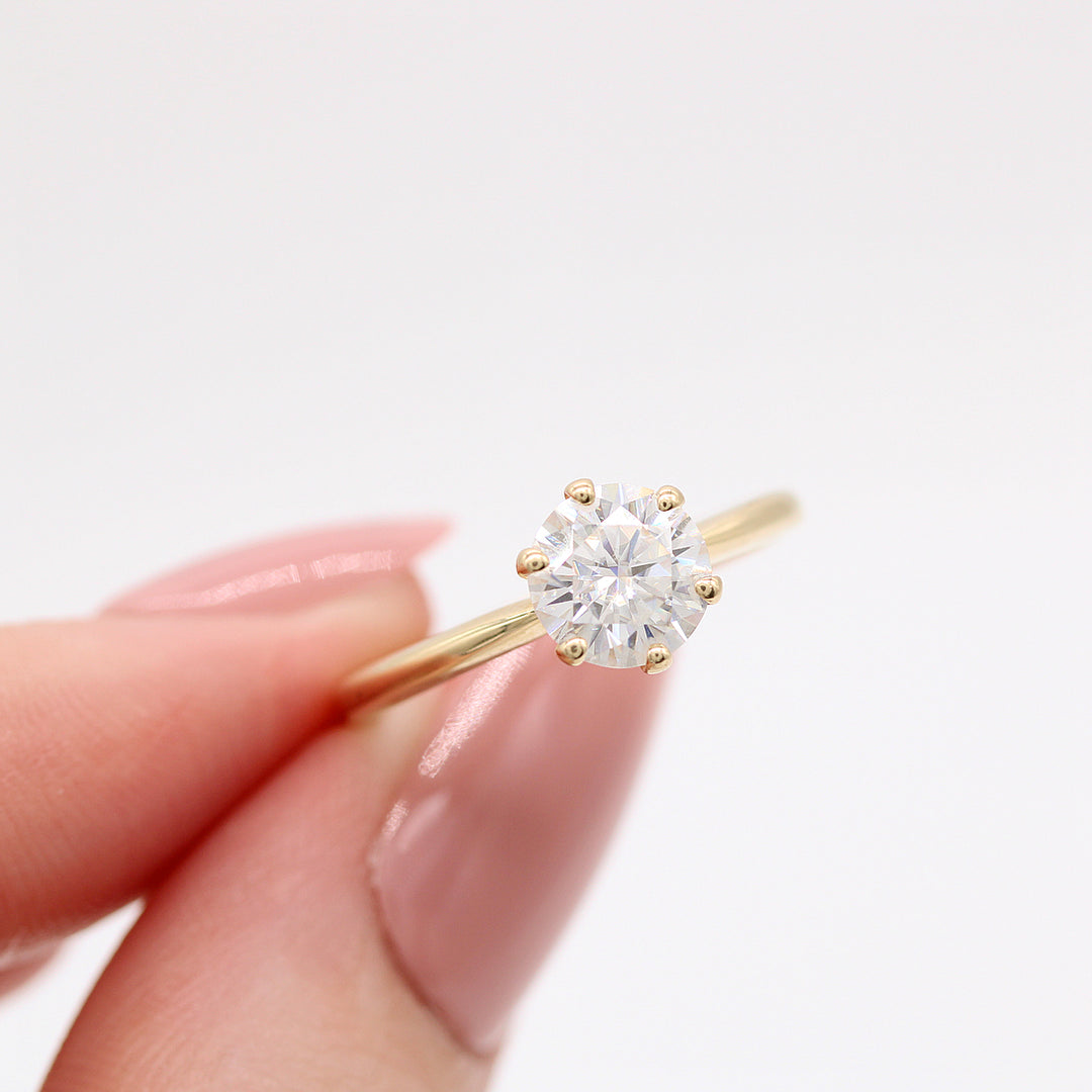 The Audrey ring in yellow gold held by a finger