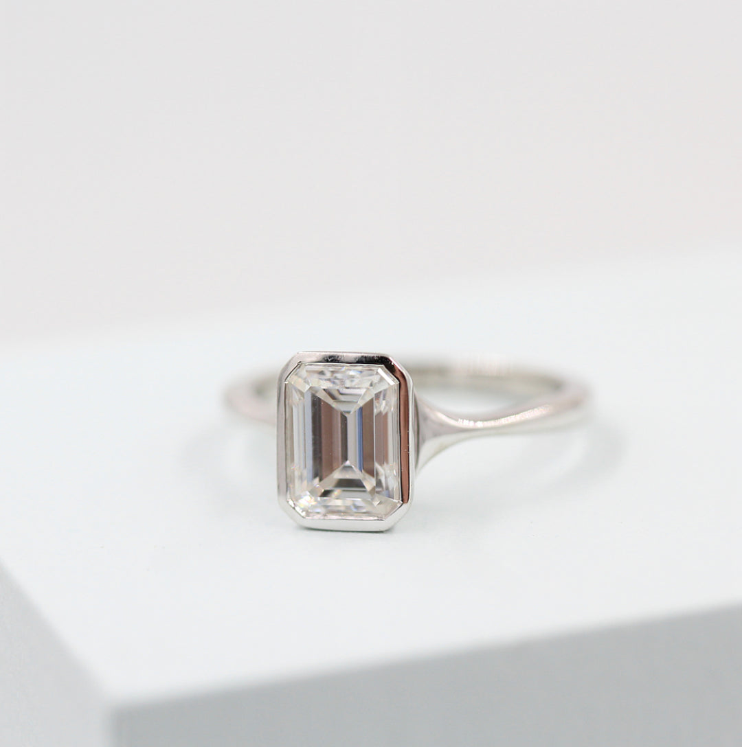 White gold bezel solitaire engagement ring with emerald-cut lab-grown diamond