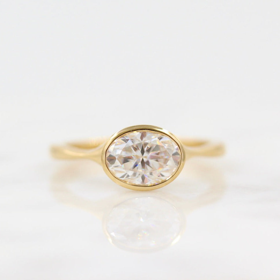 Horizontally-set oval bezel solitaire engagement ring in yellow gold