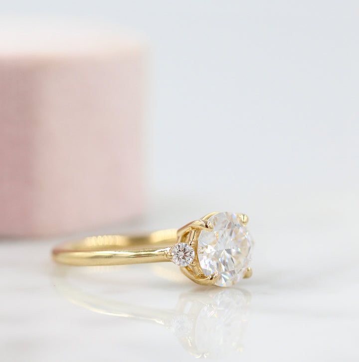 Side shot of yellow gold engagement ring showing off a round accent diamond