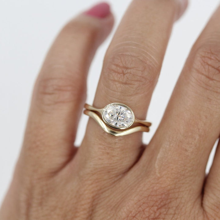 Hand wearing minimalist engagement ring wedding set in yellow gold