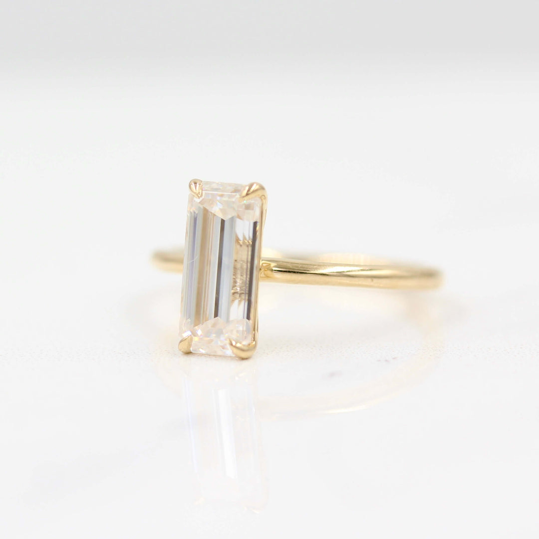 Angled shot of an elongated emerald solitaire engagement ring