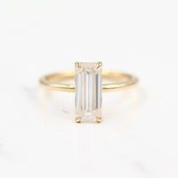 14k yellow gold elongated emerald solitaire engagement ring on a white background