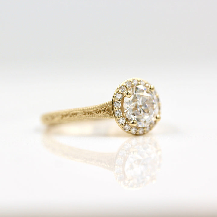 Round yellow gold halo engagement ring with scrollwork on band