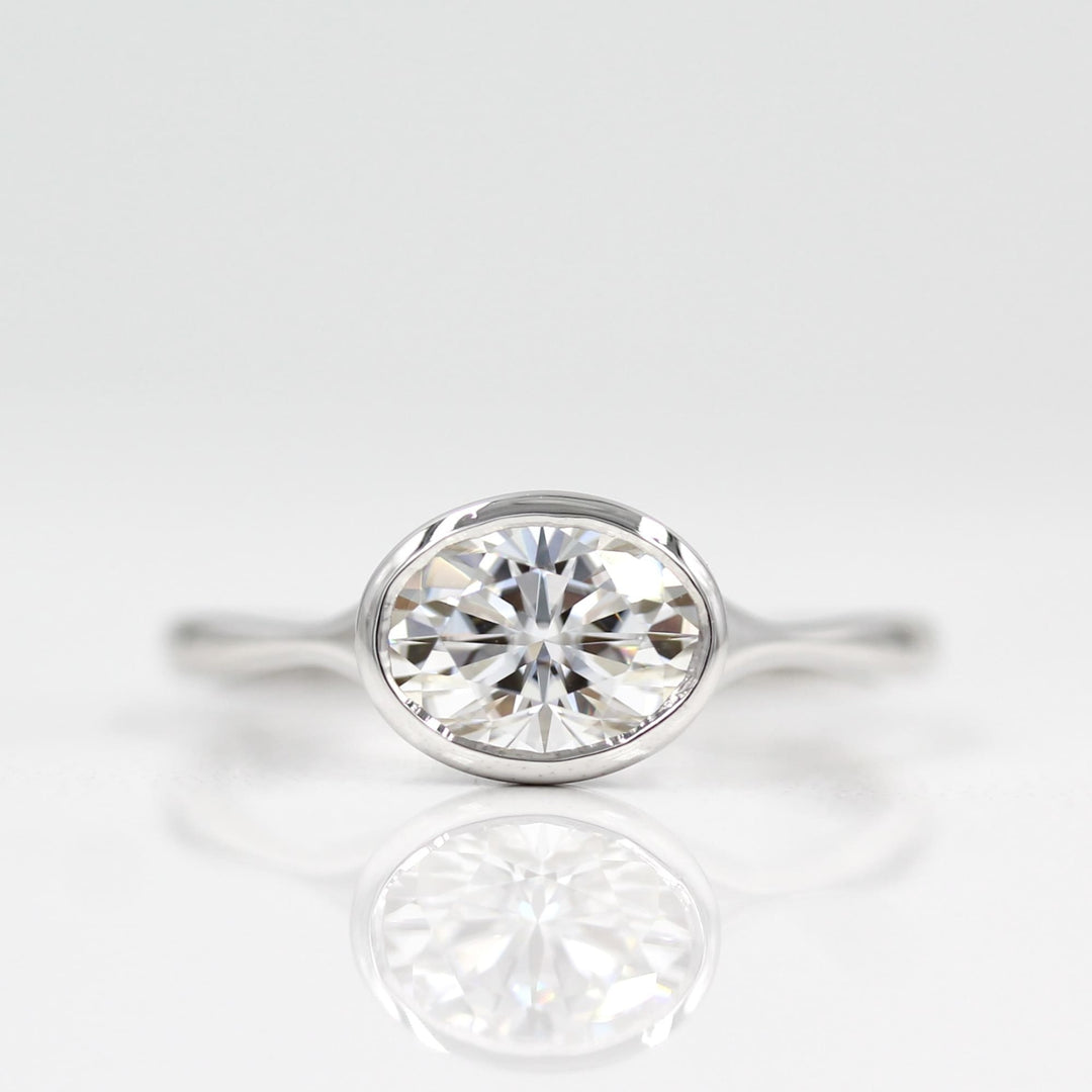 Horizontally-set oval lab grown diamond in white gold bezel solitaire setting