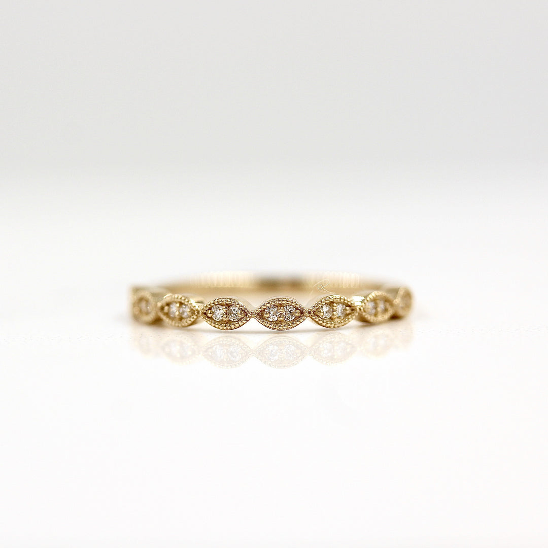 a gold scalloped wedding band on a white surface