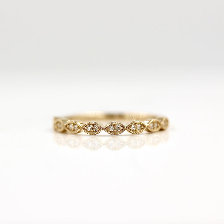 a gold scalloped wedding band on a white surface