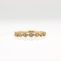 a gold scalloped wedding band on a white surface