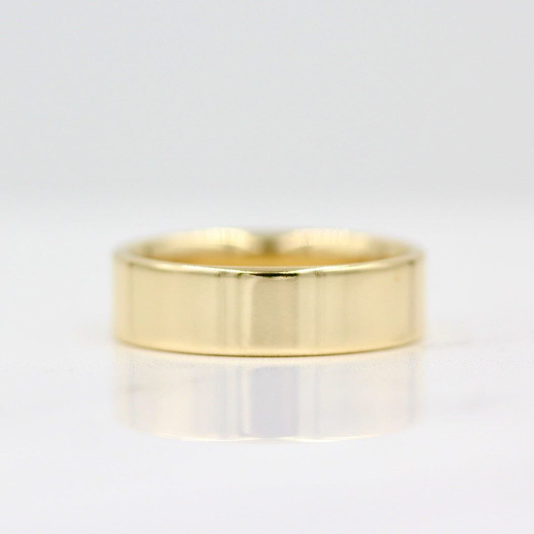 a thick gold wedding band on a white surface