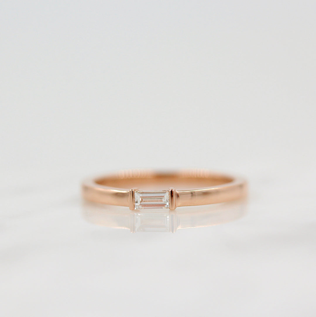 a rose gold baguette diamond ring on a white surface