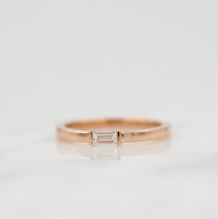 a rose gold baguette diamond ring on a white surface